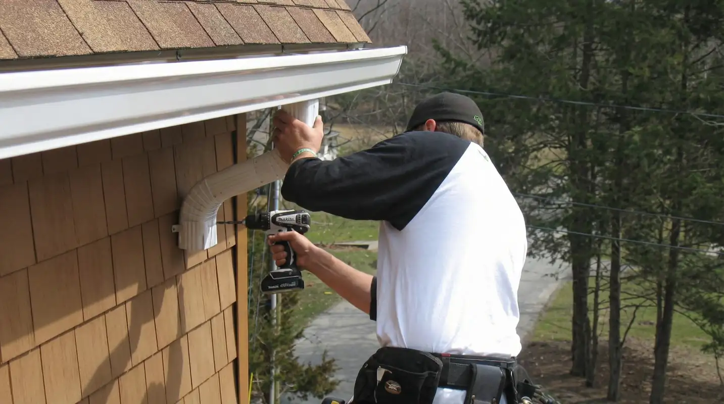 Professional contractor installing tan vinyl siding panels on a residential home exterior in Knoxville, TN